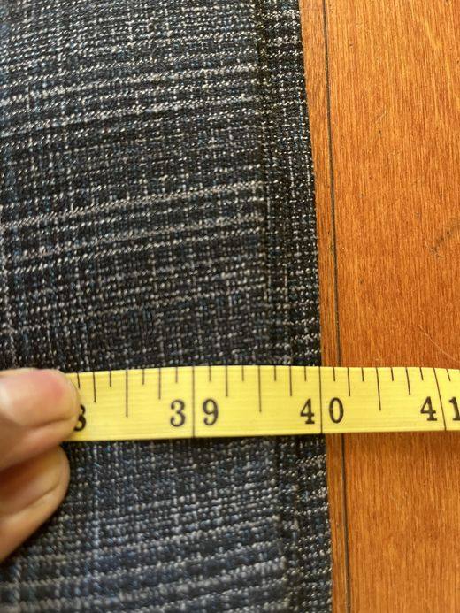 A yellow tailor's tape measuring a gray plaid fabric at about 40 inches