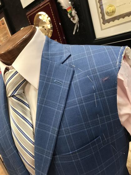Close-up of a blue windowpane jacket on a form, marked with white basting thread for adjustments