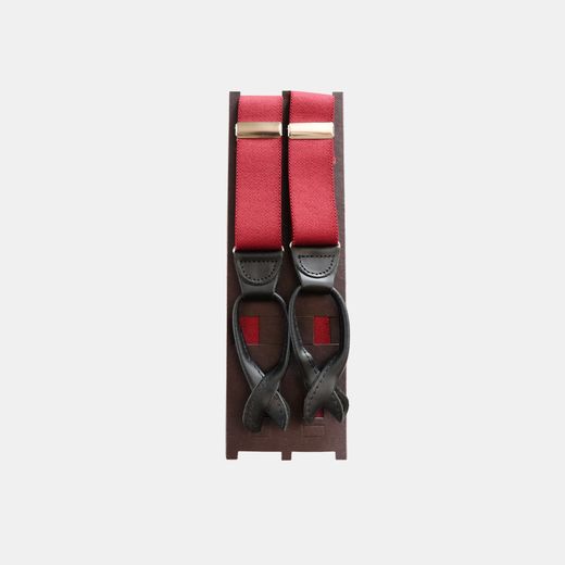 Red and black suspenders with leather button tabs on a wooden stand
