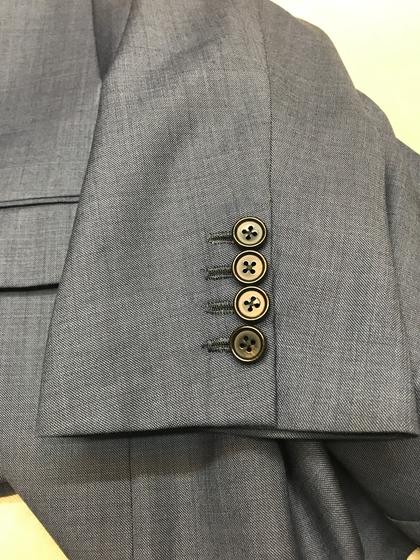 Close-up of a gray suit sleeve with four stacked horn-style buttons